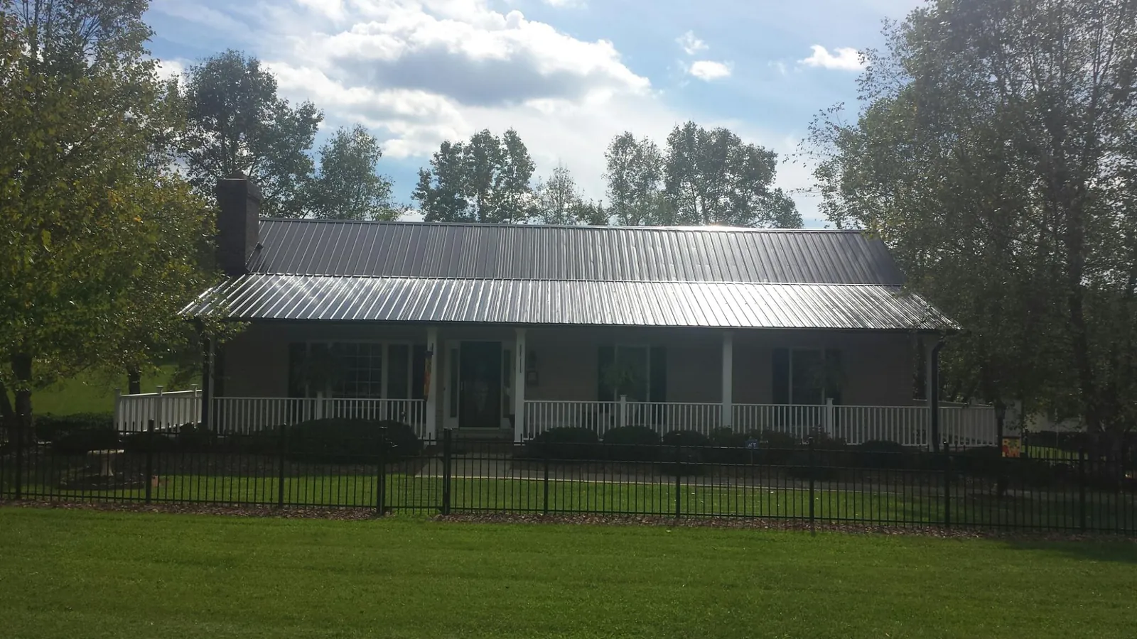 Gray metal roof on a brick ranch with a full width front porch — Gutter Guard Installation work by our crew in Barnesville